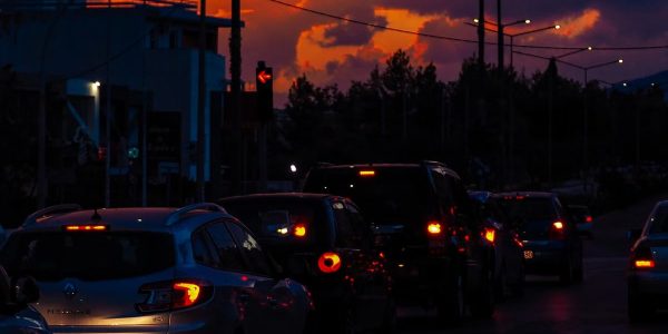 Cars lined up on a street at dusk with a vibrant sunset sky creating a dramatic silhouette scene.